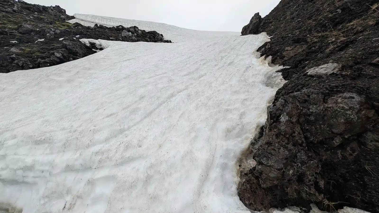 Snowfield between dark volcanic rocks in the Icelandic highlands