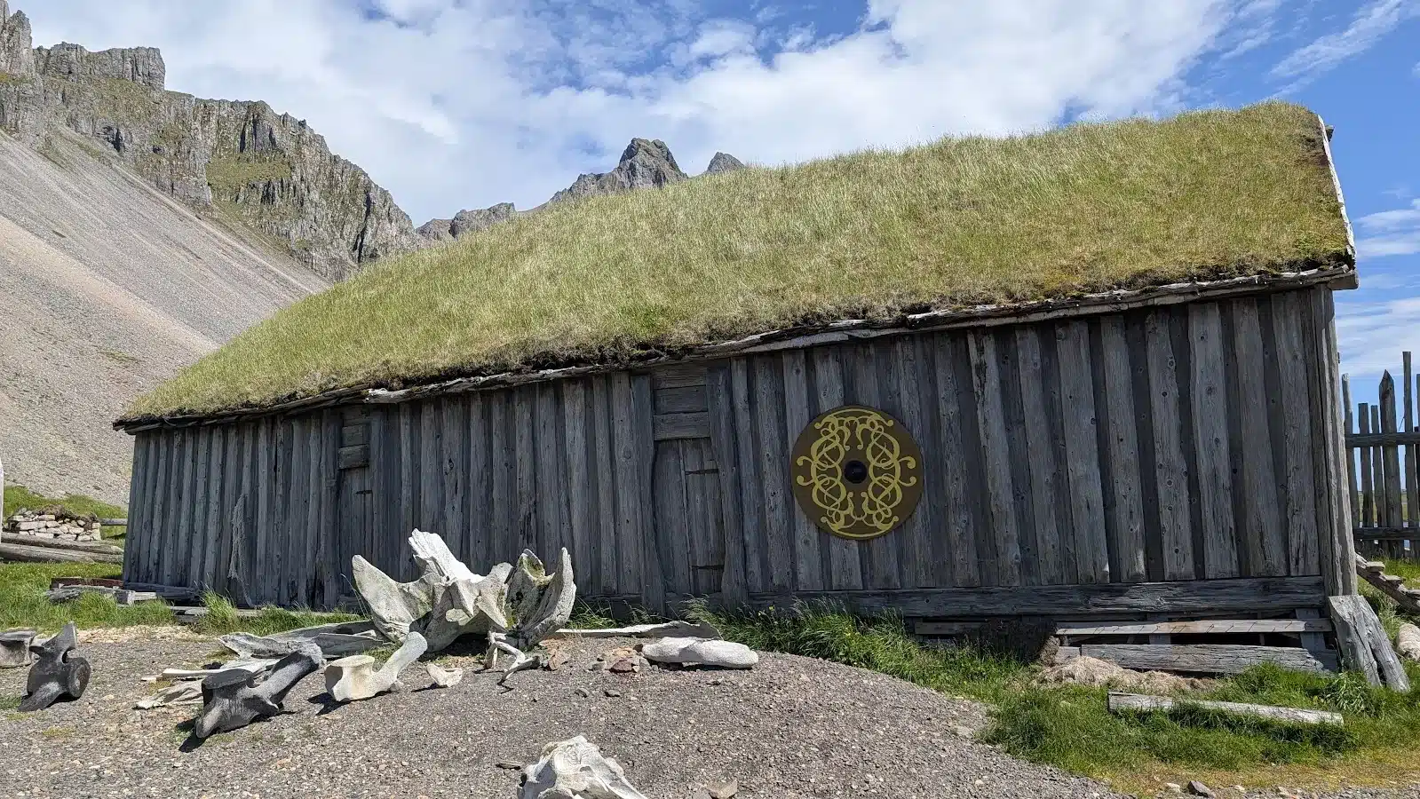 Turf-roofed wooden house with whale bones beneath Icelandic mountains