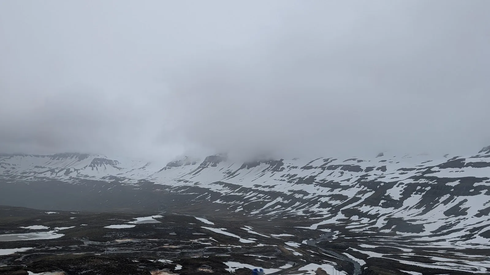 Snow-streaked Arctic mountains fading into low cloud